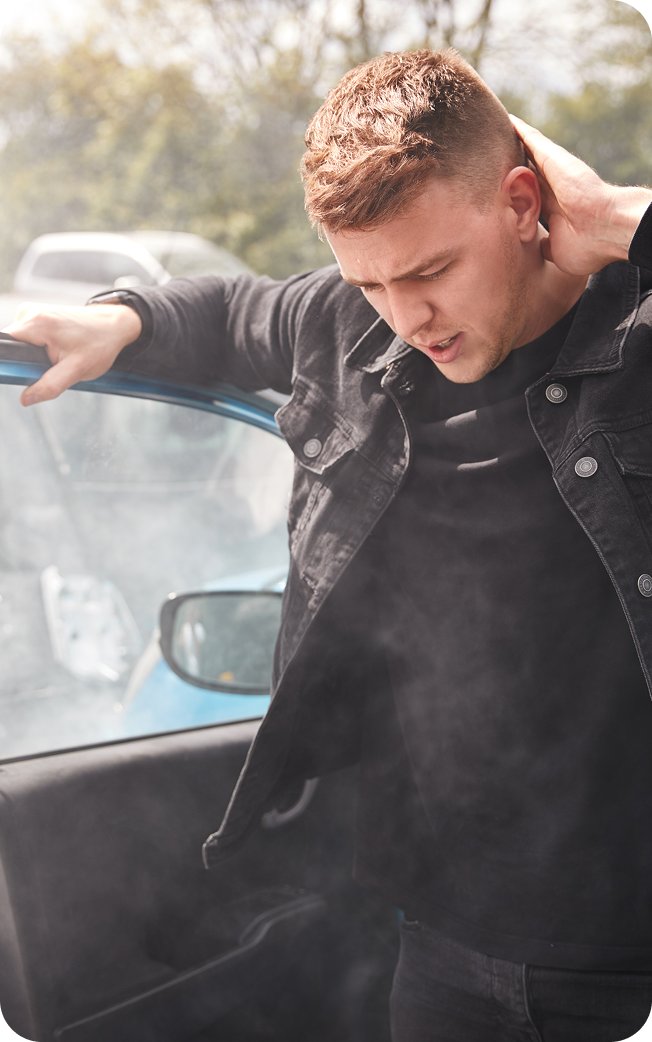 Man holding his neck beside his car after an accident