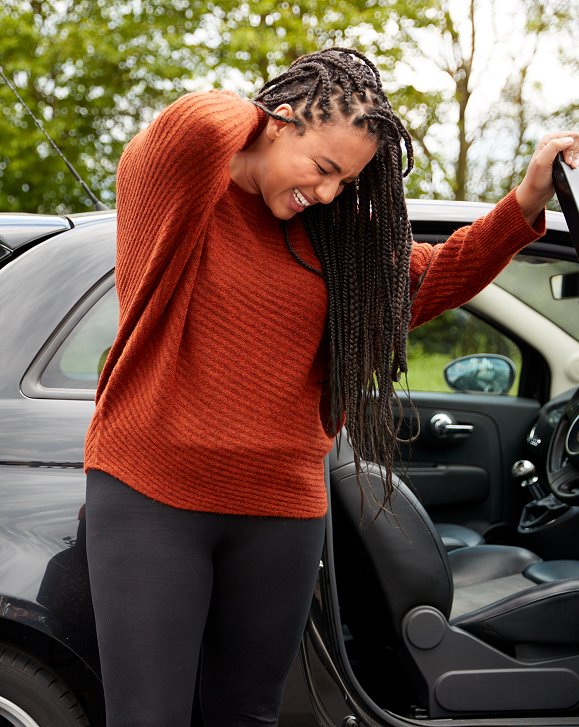 Woman holding her neck in pain while getting out of her car
